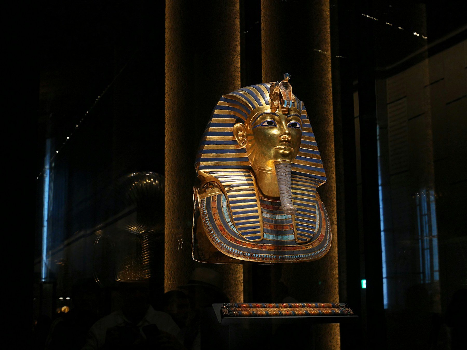 The golden funerary mask of Tutankhamun displayed in a darkened gallery
